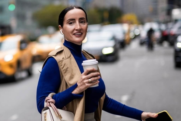 Woman crossing busy street carrying a coffee